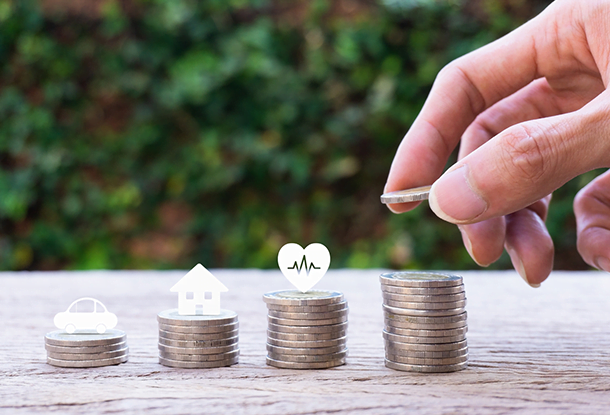 image: hand setting down coins in stacks with icons above (iStockphoto)