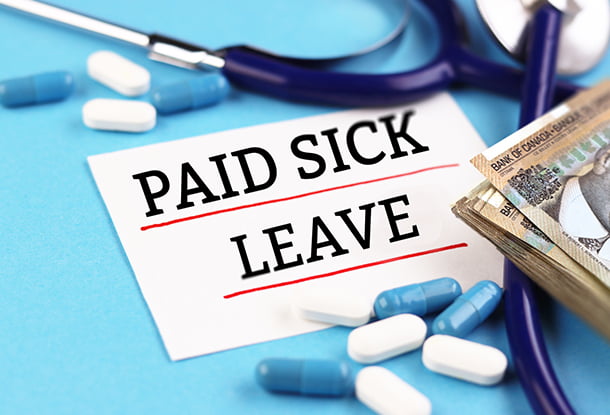 photo composition: medical equipment, pills, money and a note reading "Paid Sick leave" (iStockphoto)